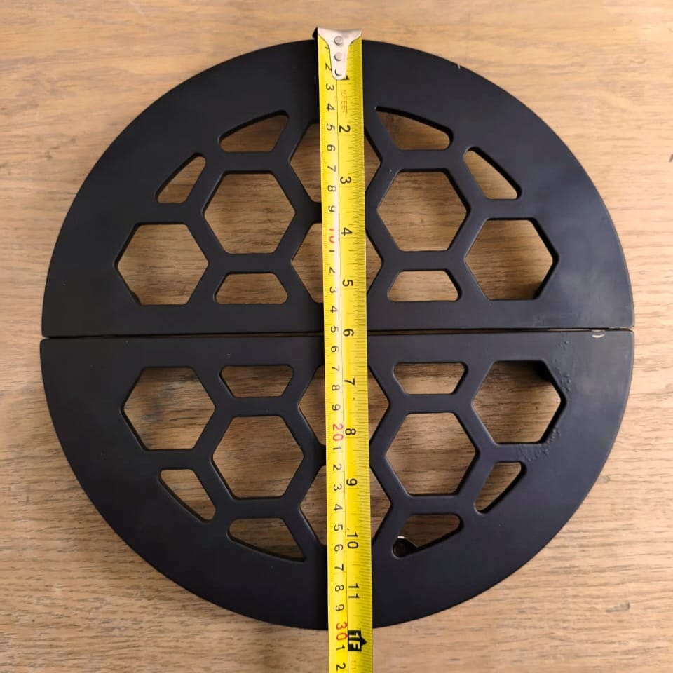 Black metal reel with hexagonal pattern on a wooden surface, measured by a tape measure.