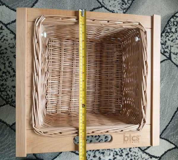 Wooden box with wicker interior and measuring tape for size, on a textured surface.