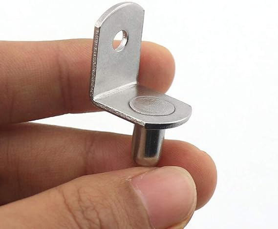 Metal bracket held between fingers against a white background