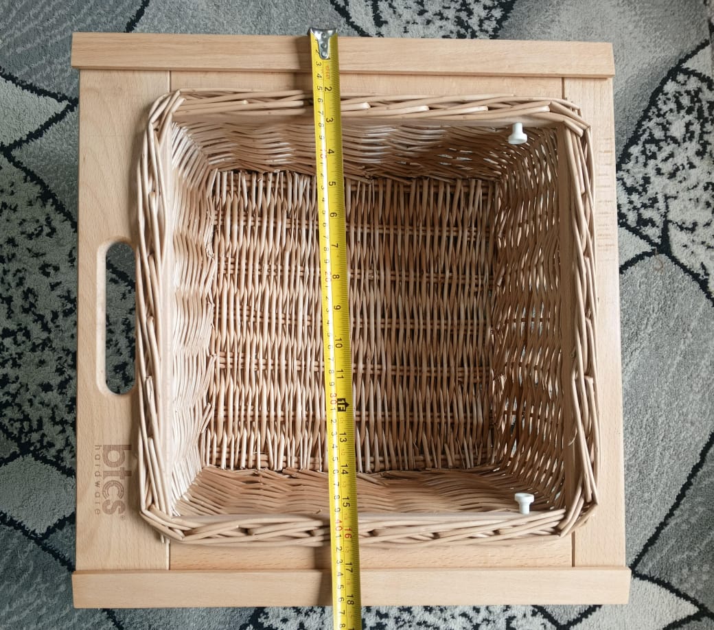 Wicker basket with a measuring tape showing its dimensions on a textured surface.
