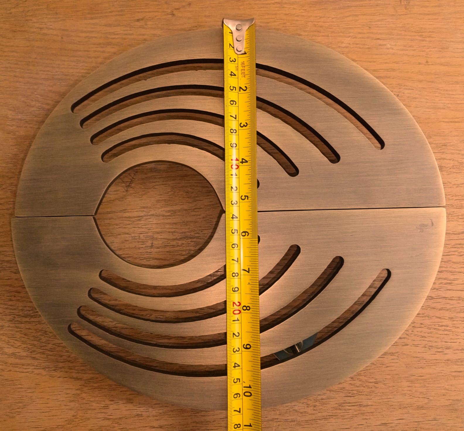 Wooden circular object with measurement tape for scale on a wooden background